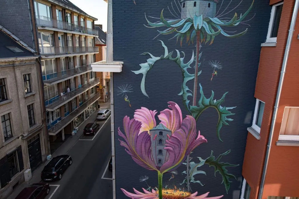 Grande fresque de plantes sauvages et de fleurs géantes sur le pignon d’un immeuble à Namur
