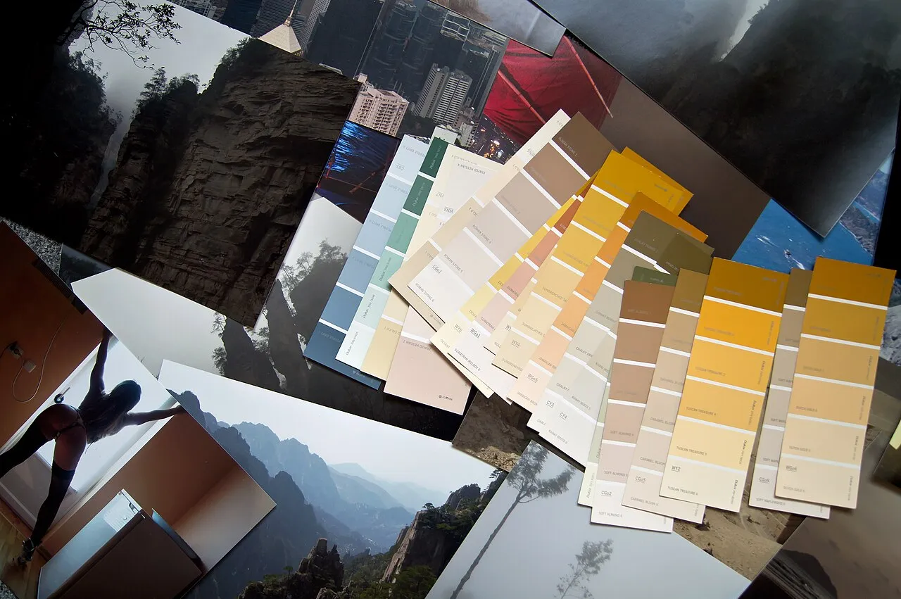 Collage de photographies de paysages et nuanciers de peinture en éventail posés sur une table