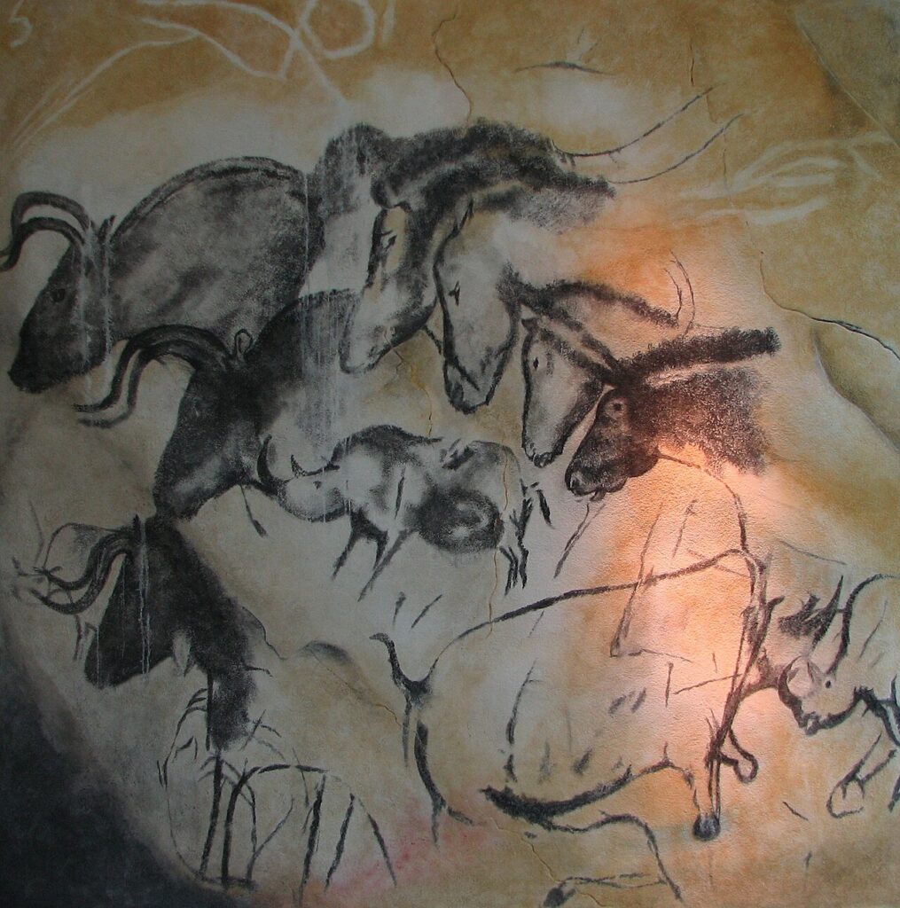 Réplique des peintures de la grotte Chauvet : chevaux, aurochs et rhinocéros dessinés au noir sur la roche