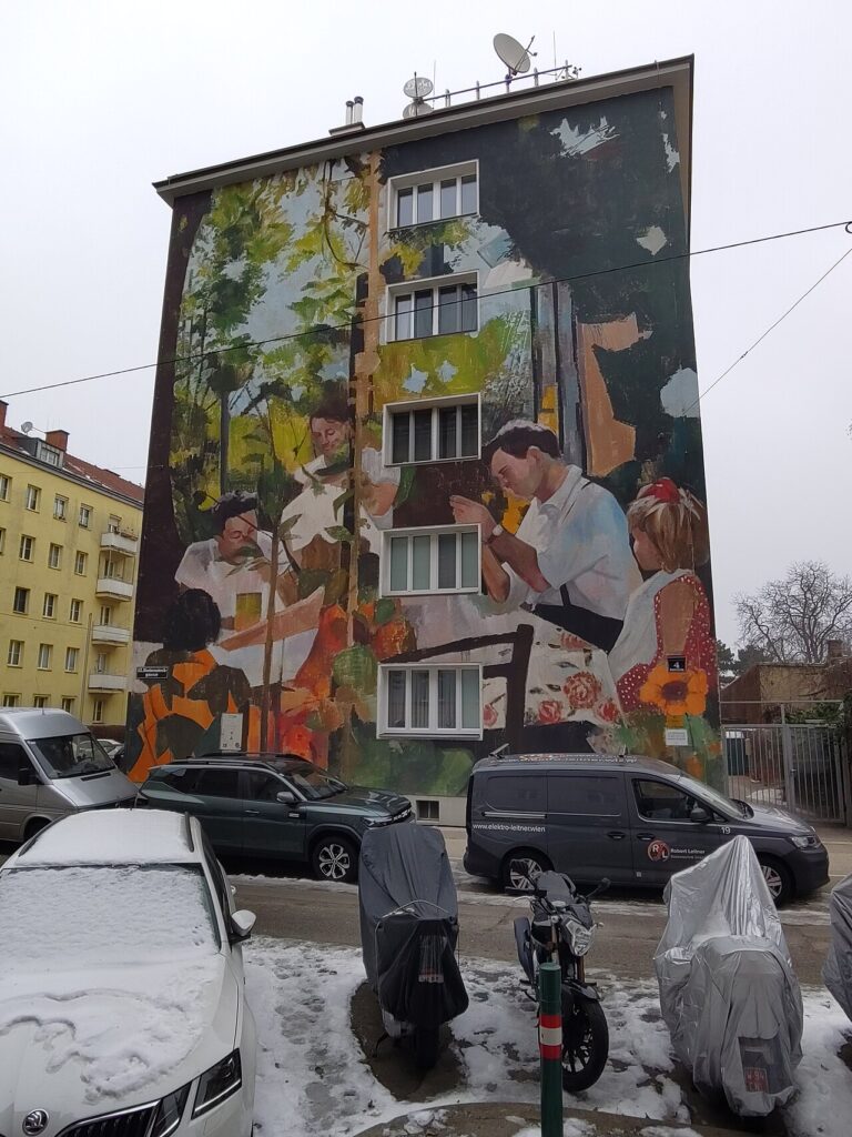 Façade d'immeuble couverte d'une fresque réaliste montrant une famille attablée dans un jardin