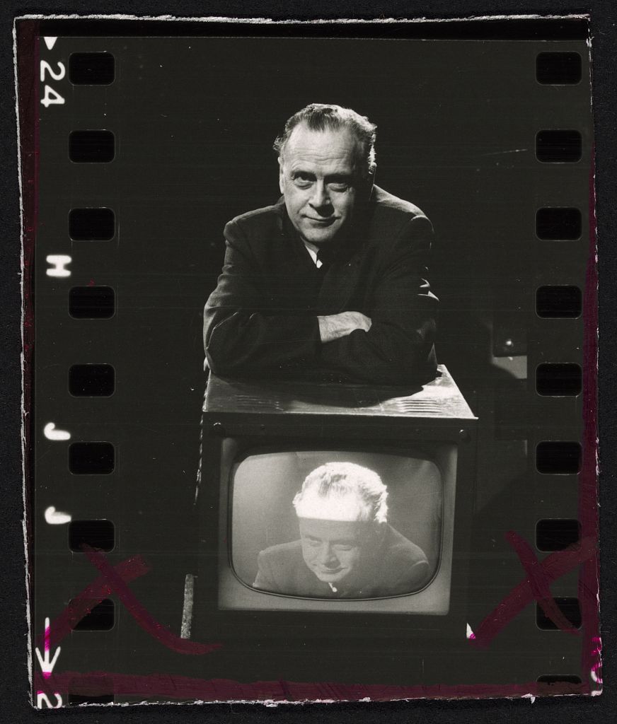 Marshall McLuhan appuyé sur un téléviseur qui diffuse sa propre image, photo noir et blanc